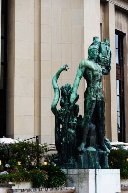 Büyük bronz heykel şehir binasının önünde duruyor. Kamu sanatı, şehir mimarisi ve turizmi için kültürel bağlam sağlıyor.