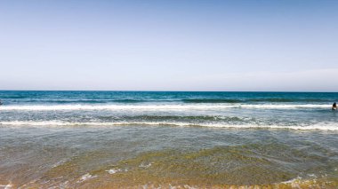 Açık mavi deniz suyu, güneşli sahilde mavi gökyüzünün altında dalgalar. Seyahat, tatil ya da dijital ya da basılı projelerde doğa geçmişi için. Metin için alanı kopyala