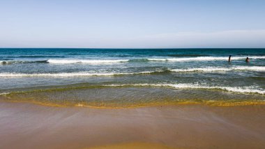Açık mavi deniz suyu, güneşli sahilde mavi gökyüzünün altında dalgalar. Seyahat, tatil ya da dijital ya da basılı projelerde doğa geçmişi için. Metin için alanı kopyala