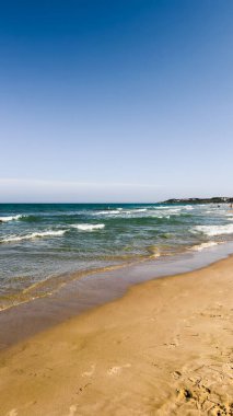 Açık mavi deniz suyu, güneşli sahilde mavi gökyüzünün altında dalgalar. Seyahat, tatil ya da dijital ya da basılı projelerde doğa geçmişi için. Metin için alanı kopyala