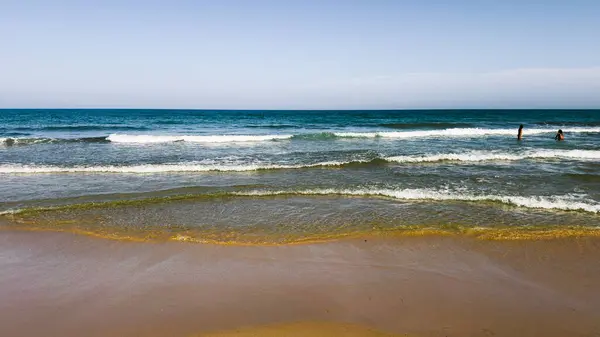 Açık mavi deniz suyu, güneşli sahilde mavi gökyüzünün altında dalgalar. Seyahat, tatil ya da dijital ya da basılı projelerde doğa geçmişi için. Metin için alanı kopyala