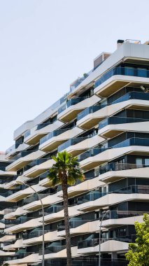 Dalgalı beyaz balkonları ve cam dış yüzeyi olan çağdaş konutlar. Şehir yaşamı ve emlak pazarlama amaçları için kentsel konut yapısı.