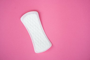 Pembe arka planda izole edilmiş tek bir beyaz hijyenik ped. Kadın hijyeni, regl dönemi ve kişisel bakım ürünleri reklamına uygun konular.