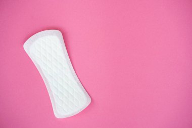 Tek bir beyaz hijyenik ped, düz pembe bir zemin üzerinde izole edilir. Dokusunu ve şeklini açıkça gösterir. Kadın hijyeni, regl dönemi ve kişisel bakım ürünleri reklamına uygun konular.