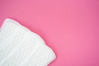 Pembe arka planda izole edilmiş beyaz hijyenik pedler. Kadın hijyeni, regl dönemi ve kadın sağlığı konularına uygundur..