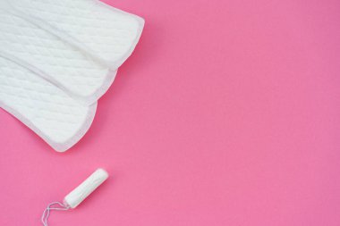 Beyaz hijyenik pedler ve pembe arka planda izole edilmiş tek bir tampon. Kadın hijyeni, adet görme ve kadın sağlığı eğitimi konularına uygundur..