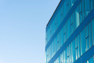 Mavi camlı, temiz gökyüzünü yansıtan çağdaş ofis binası, temiz çizgiler ve modern mimari gösteriyor. Sunumlarda, web sitelerinde iş, şirket veya kentsel gelişim kavramlarını resmetmeye uygundur.