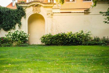 Süslü taş kemer yolu, yemyeşil çalılar, ortancalar ve manikürlü otlarla çevrili bir krem duvarın içinde. Tarihi bahçeleri, peyzajı ya da sakin açık alanları resmetmeye uygundur..