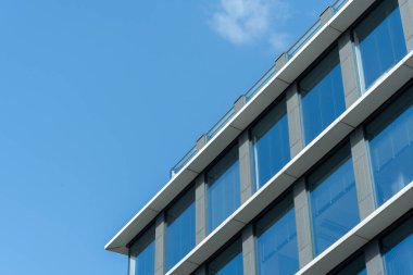 Çağdaş ofis binasının dış tarafında mavi cam pencereler ve açık mavi gökyüzü var. Kentsel gelişimi, iş altyapısını veya modern mimari kavramları göstermek için.