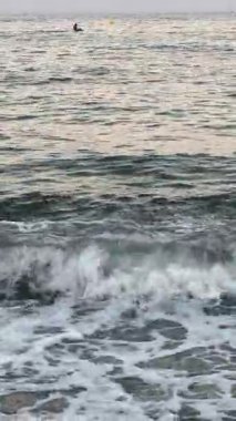 Yumuşak deniz dalgaları güneş ışığı altında kumlu kıyıya yavaşça yuvarlanıyor. Yüksek kalite 4k görüntü