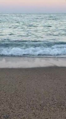 Yumuşak Pembe Dalga Alacakaranlık 'ta yuvarlanıyor, Romantik ve Hayalperest Ruh hali için Gentle Ocean Beach arka planı. Yüksek kalite 4k görüntü