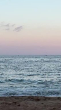 Yumuşak deniz dalgaları güneş ışığı altında kumlu kıyıya yavaşça yuvarlanıyor. Yüksek kalite 4k görüntü