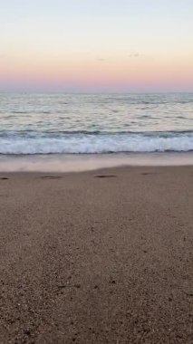 Yumuşak Pembe Dalga Alacakaranlık 'ta yuvarlanıyor, Romantik ve Hayalperest Ruh hali için Gentle Ocean Beach arka planı. Yüksek kalite 4k görüntü