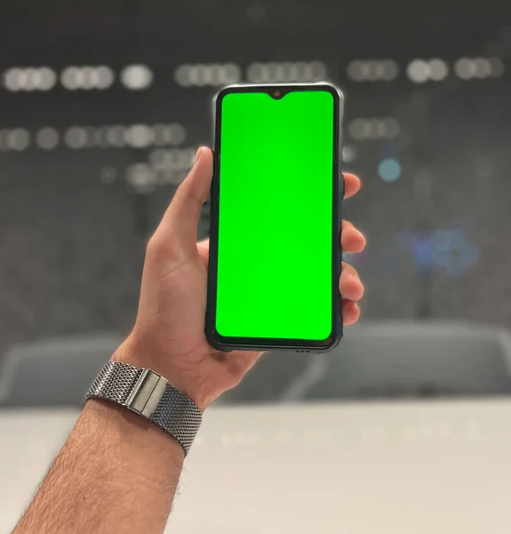 man hand holding a green screen smartphone with the blank display