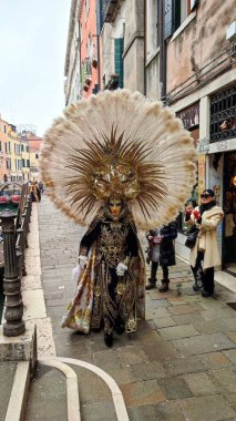 A man in a carnival mask walks down the street