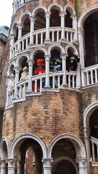 people in carnival masks stand on the old tower