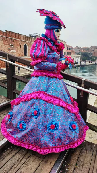 Woman in carnival costume and mask on the bank of the canal