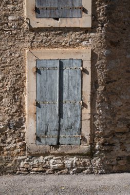 Fransa 'da bir köyde eski bir evin köşesindeki eskimiş mavi panjurlar ve pencereler.
