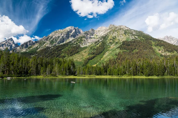 Dağlar ve Wyoming Grand Teton Ulusal Parkı 'ndaki String Gölü' nün berrak ve sakin sularının üzerindeki dramatik gökyüzü.