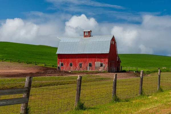 Tipik bir Amerikan kırsal kesiminde, Washington, Palouse Hills 'de kırsal bir kırmızı ahır ve çit var.