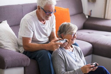 Kafkasyalı emekli yaşlılar evlerinde kanepede oturup oyun oynuyorlar, ellerinde kumanda ya da joystick tutuyorlar.. 