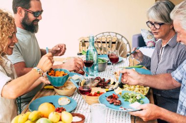 Aile hayatının güzel bir anı. Evde yemek yemek ya da masada içki içmek. Güneş gözlüklü bir adam, dışarıda yemek ve salata dolu bir masa alıyor.   