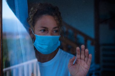 Kapalı alanda karantina altındaki pencereden dışarı bakan bir kadının portresi. Koronavirüsü veya herhangi bir tür hastalığı önlemek için kovid-19 kullanan yetişkin bir kadın. 