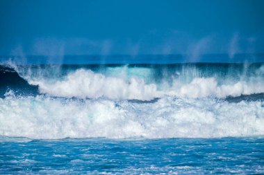 Beautiful Tropical Island Paradise Photo of Clear Aqua Blue Ocean Wave Crashing on Rocks with Sun Rays Coming Though Clouds of Colorful Pastel Sunset Sky at Dusk on Maui Hawaii  clipart