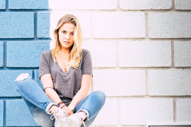 Mavi gözlü güzel kadın kameraya bakıyor. Mavi ve beyaz arkaplanlı fotoğrafa poz veriyor. 