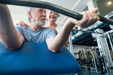 Son sınıf öğrencileri spor salonunda birlikte egzersiz yapıyor, ağırlık kaldırıyor. İki mutlu emeklinin spor yapıp spor yaptığı spor yapıyor. 