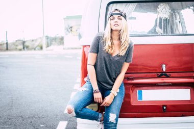 beautiful blonde woman with blue eyes looking at the camera - adult with great red and white van - lifestyle concept - lady stand with red and white van  in a street and urban place  clipart