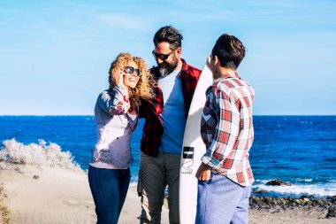 Güneşli bir günde sonsuza dek sahilde birlikte güzel bir aile ve sörfçü genç - sörf masası ve mutlu insanlarla sohbet - yaz tatili - arka plan 