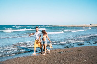 Sahilde mutlu mesut yürüyen iki yetişkin ayaklarında su, arka planda deniz - kollar açık ve özgürlük kavramı 