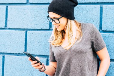 Sadece akıllı telefonunu tutan ve kullanan mutlu bir kız. Telefonuyla oynayan beyaz bir kadın. Milenyum 20 'li yaşlarda gözlüklü. 