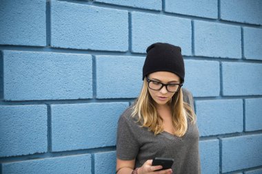 Sadece akıllı telefonunu tutan ve kullanan mutlu bir kız - telefonuyla oynayan beyaz bir kadın - 20li yaşlarda gözlüklü. 