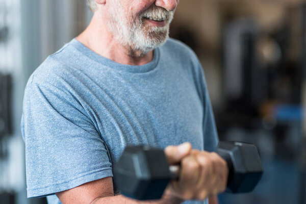 adult man and mature senior at the gym working his body with dumbbell - one man happy training indoors 