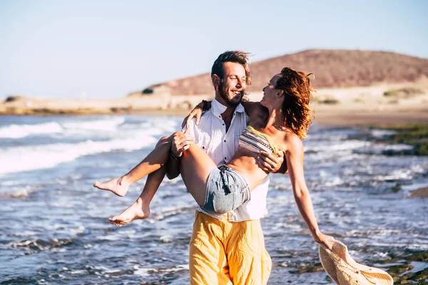一对年轻漂亮的夫妇正在度假和度假 一个男人在海滩上抱着一个有爱心的女人 — 图库照片