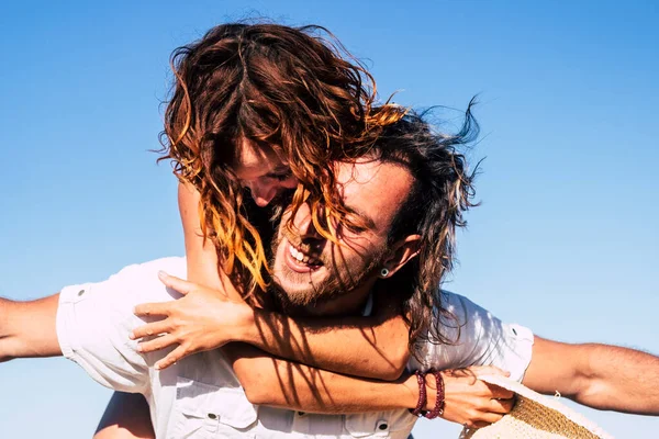 stock image beautiful couple of adults having fun together at the beach on the sand - man walking with his wife or his girlfriend on he - he's holding she - woman with arms open be happy 