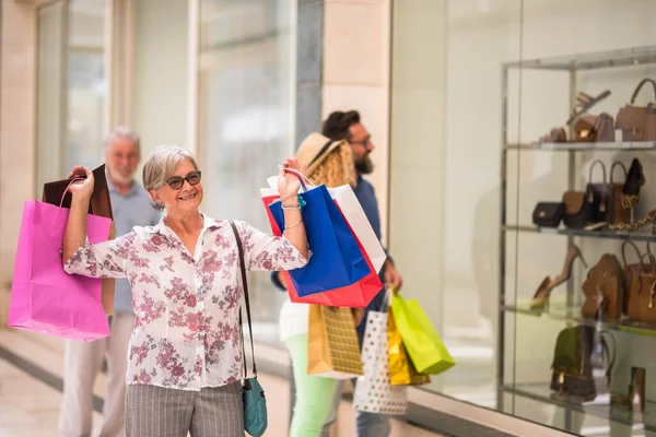 stock image one mature woman at the mall going shopping with her husband - senior holding some bags smiling  