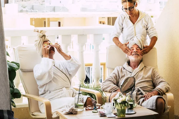 stock image beauty farm in the terrace of home with assistance doing a massage on the face of mature man - seniors relaxing together 