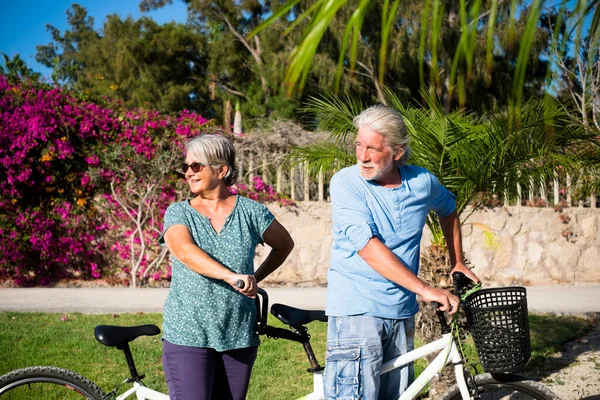 beautiful couple of senior and mature married, riding a double bike, tandem, together to have fun with a great and sunny day - looking at the back