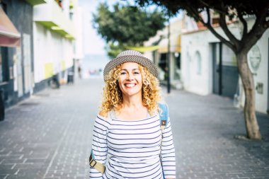 Genç, güzel, kıvırcık bir kadının portresi. Sokakta yürürken kameraya bakıyor. Yeni yerler keşfediyor ve geziyor. 