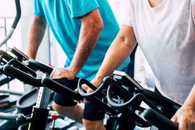 Spor salonunda iki son sınıf öğrencisi birlikte bisiklete biniyor. Sağlıklı yaşam tarzı kavramı. Aktif emekliler çok çalışıyor. 