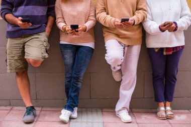 Bir grup insan cep telefonlarını ve akıllı telefonlarını birlikte kullanıyor ve ona bakıyorlar - online yaşam tarzı ve konsept - telefon ve teknolojiye bağımlı 