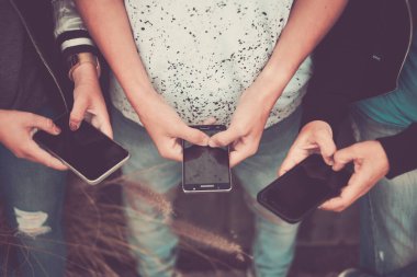 Bir grup insan yeşil arka planda telefonlarını kullanıyor. Mutlu arkadaşlar çalışıyor ya da ellerinde akıllı telefonları tutuyorlar- Kafkas açık havada. 