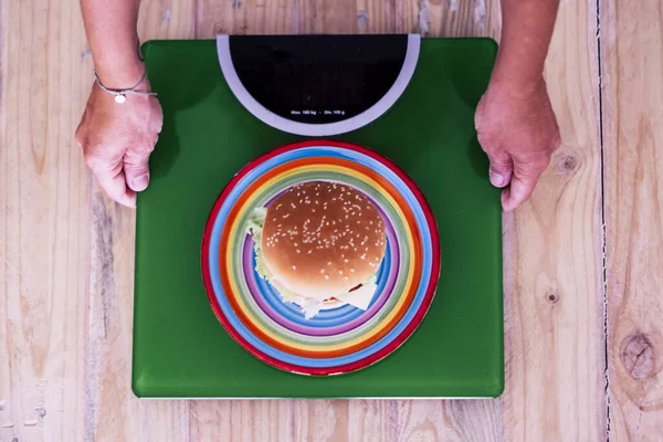 Yeşil kiloda hamburgere bakan kadın - aklı başında ve sağlıklı yaşam tarzı konsepti 