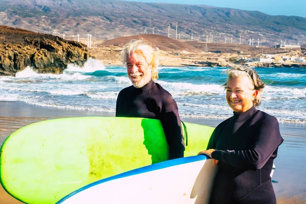 大きなサーフボードと一緒にビーチで一緒にサーフィンする大人と高齢者のカップル 夏を楽しんで楽しむ2人の高齢者ウォータースポーツ屋外 — ストック写真