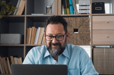 İnternette çalışırken gülümseyen genç beyaz iş adamı laptopta webinar podcast izliyor ve eğitim konferansını öğreniyor notlar alıyor çalışma masasına oturuyor, e-öğrenim kavramı oluşturuyor. 