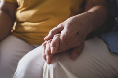 Evde birbirini kollayan iki elin yakınlaşması. Yaşlı ve olgun insanların elleri. 