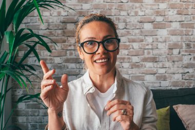Çekici, gülümseyen, kıvırcık bir kadının yakın plan portresi. Hoş bir milenyum kızı kameraya bakıyor, ailesiyle video görüşmesi yapıyor ya da evdeki kişisel kanal için video kaydediyor.. 
